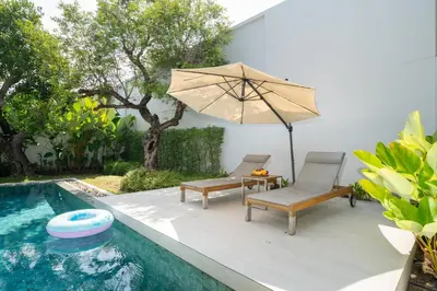 a patio with two chairs and an umbrella next to a swimming pool at Villa Beautiful swimming pool in Phuket