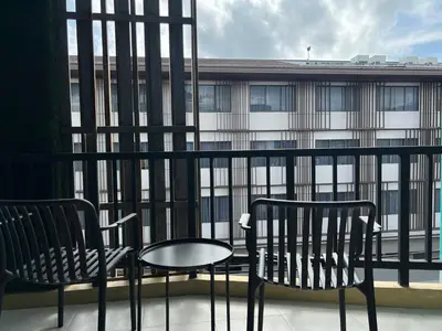 a balcony with two chairs and a table and a building at The Sealect Hotel in Kata Beach