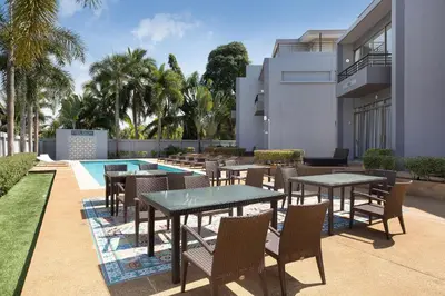 a patio with tables and chairs next to a swimming pool at 3BR Pool Access Villa near Mission Hills Golf - Argent 7 in Ban Muang Mai