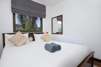 a bedroom with a white bed with two windows at 3BR Pool Access Villa near Mission Hills Golf - Argent 7 in Ban Muang Mai