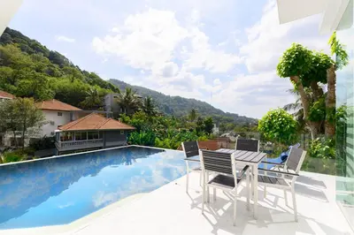a patio with a table and chairs next to a swimming pool at Villa Beverly Private Infinity Pool with Seaview near Kata Beach in Kata Beach