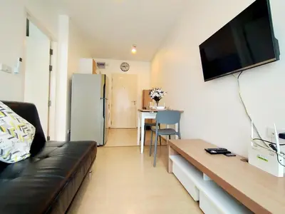 a living room with a black leather couch and a flat screen tv at Cozy room near beaches & restaurants in Bang Tao Beach