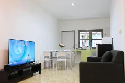 a living room with a tv and a table with chairs at Sisters Ari 2-bedrooms house, Bang Tao beach in Ban Thalat Choeng Thale