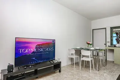 a living room with a tv and a table with chairs at Sisters Ari 2-bedrooms house, Bang Tao beach in Ban Thalat Choeng Thale