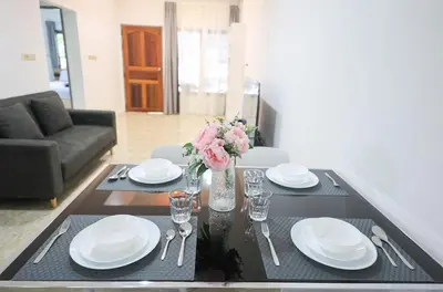 a dining room table with plates and a vase of flowers at Sisters Ari 2-bedrooms house, Bang Tao beach in Ban Thalat Choeng Thale