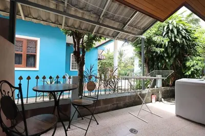 a patio with a table and chairs and a blue wall at Sisters Ari 2-bedrooms house, Bang Tao beach in Ban Thalat Choeng Thale