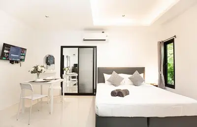 a white bedroom with a bed and a table at SOMAN apartments Bang-Tao beach in Phuket Town