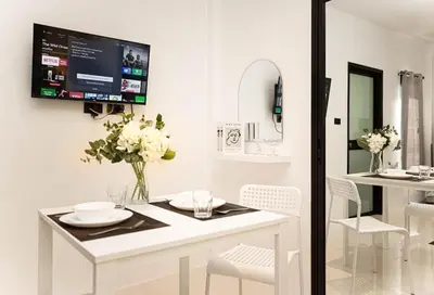 a white dining room with a tv on the wall at SOMAN apartments Bang-Tao beach in Phuket Town