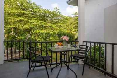 a table on a balcony with two chairs and flowers at SOMAN apartments Bang-Tao beach in Phuket Town