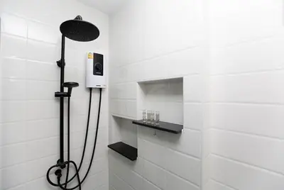 a shower in a white tiled bathroom at SOMAN apartments Bang-Tao beach in Phuket Town