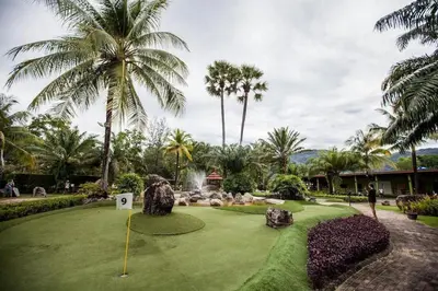 a putting green with palm trees and a golf course at Sam's Unique and Stylish houses, 10 min to the beach in Ban Thalat Choeng Thale