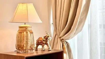 a lamp sitting on a table next to a curtain at Stylish Family Townhouse 3 Bdr in Chalong