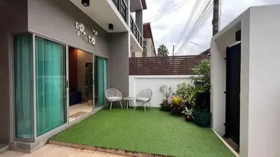 a patio with two chairs and a green lawn at Stylish Family Townhouse 3 Bdr in Chalong