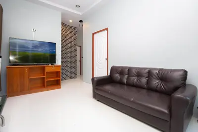 a living room with a leather couch and a flat screen tv at Tutu house, walking distanse to Bang Tao beach in Bang Tao Beach