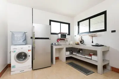 a kitchen with a refrigerator and a desk and a washing machine at Japanese houses in Phuket in Ban Thalat Choeng Thale