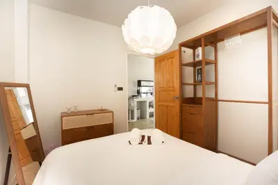 a bedroom with a white bed and a chandelier at Japanese houses in Phuket in Ban Thalat Choeng Thale