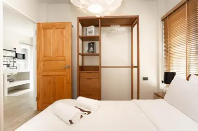a bedroom with a white bed with towels on it at Japanese houses in Phuket in Ban Thalat Choeng Thale
