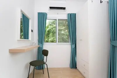 a room with blue curtains and a chair and a window at Japanese houses in Phuket in Ban Thalat Choeng Thale