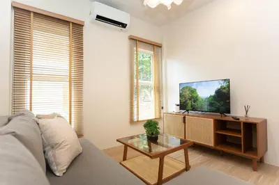 a living room with a couch and a flat screen tv at Japanese houses in Phuket in Ban Thalat Choeng Thale