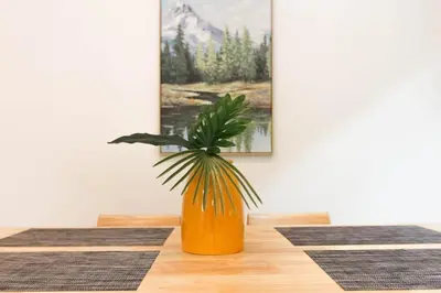 a plant in an orange vase sitting on a table at Japanese barnhouse Bang Tao beach in Ban Thalat Choeng Thale