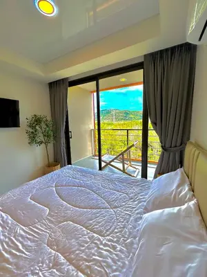 a large bed in a bedroom with a balcony at Hillside-Seashore Space Mai Khao Beach in Mai Khao Beach