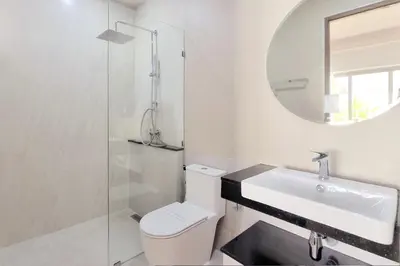 a bathroom with a toilet and a sink and a mirror at Phirunda Pool Villas in Ban Suan