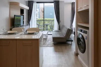 a kitchen with a washing machine and a living room at Comfy 1-BR Grand Kata VIP condo, 5 min to Kata beach in Kata Beach