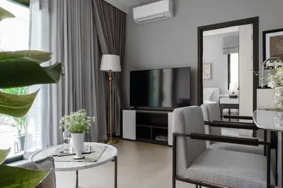 a living room with a television and a table with chairs at The Title Legendary Grand Pool Access in Bang Tao Beach
