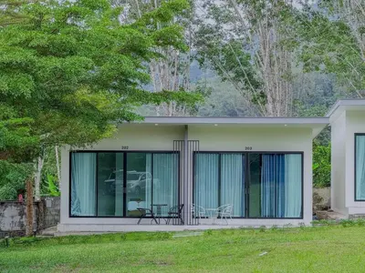 a house with glass doors and chairs in a yard at Sunisa Resort in Phuket Town