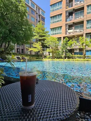 a drink sitting on a table next to a swimming pool at Valley Mountain View&City Proximity Golden Eight Apartment in Ban Phlu Yai