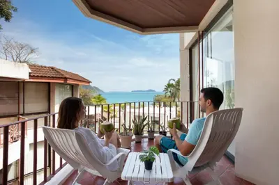 a couple sitting on a balcony with a view of the ocean at 3 BR Seaview Apt with pool access ADMC 100-2 in Ban Ao Makham