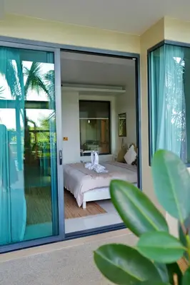 a bedroom with a bed and a sliding glass door at Spacious beautiful studio with big patio on the pool side ! in Rawai Beach