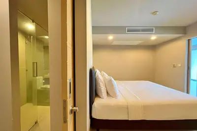 a small room with a bed and a shower at The Ark Karon Beach by RESAVA in Karon Beach