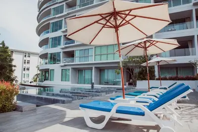 a group of lounge chairs and umbrellas in front of a building at The Ark Karon Beach by RESAVA in Karon Beach
