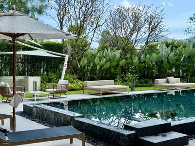 a swimming pool with lounge chairs and an umbrella at Laguna Lakeside by Villacarte in Bang Tao Beach
