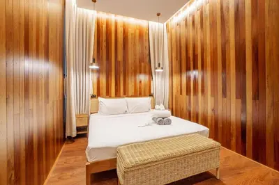 a bedroom with a white bed and wooden walls at Harley 1 BDR Condo Kata Hill, 3 Mins To kata Beach in Kata Beach