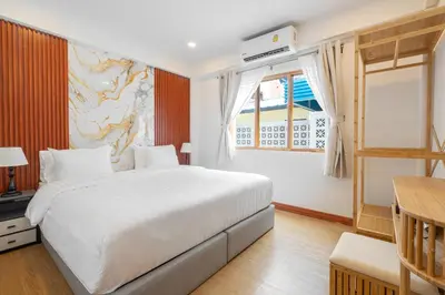 a bedroom with a large white bed and a window at The Banyan House in Patong Beach