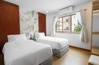a hotel room with two beds and a window at The Banyan House in Patong Beach