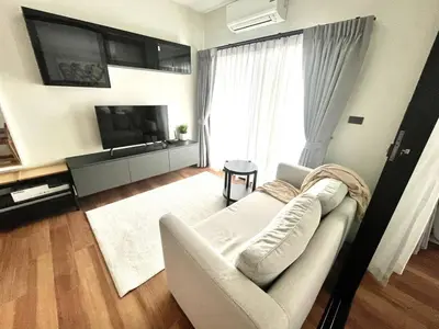 a living room with a white couch and a flat screen tv at MO607 1 br 36m in Nai Yang Beach