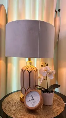 a table with a lamp and a clock and a flower at The Privilege by Tris in Patong Beach