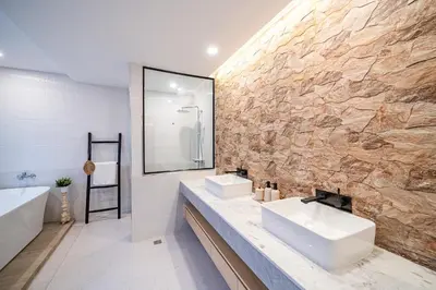 a bathroom with two sinks and a stone wall at Phu Talae Villa Rawai Beach in Ban Klang
