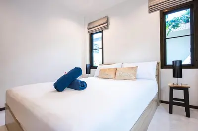a white bed with a blue stuffed animal on it at Oxavia Garden Bungalow B1 -B2 Nai Harn in Rawai Beach