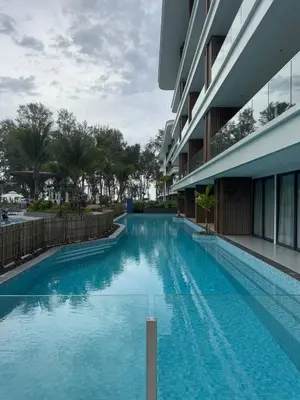 a large swimming pool next to a building at Sunshine Beach, Kora Resort Phuket 5, Bang Tao, Laguna in Bang Tao Beach