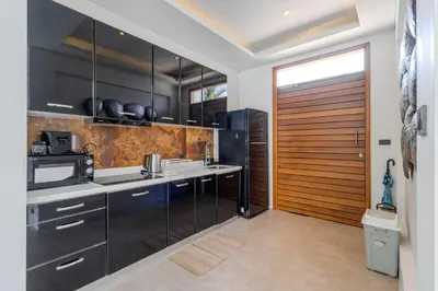 a kitchen with black cabinets and a wooden door at 2BR Modern Pool Villa Near the Sea V261 in Thalang