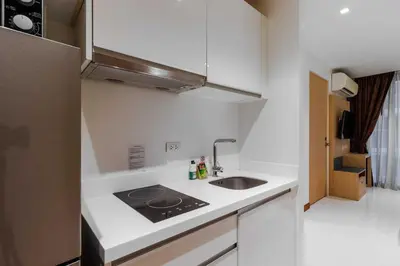 a white kitchen with a sink and a refrigerator at C244 Ocean Breeze 1BR Studio Steps from the Sea in Ban Saiyuan (1)
