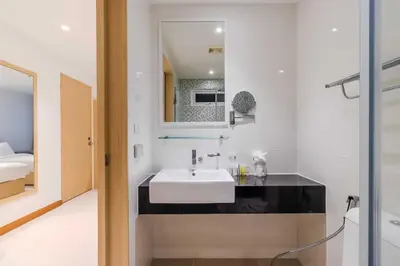 a bathroom with a white sink and a mirror at C244 Ocean Breeze 1BR Studio Steps from the Sea in Ban Saiyuan (1)