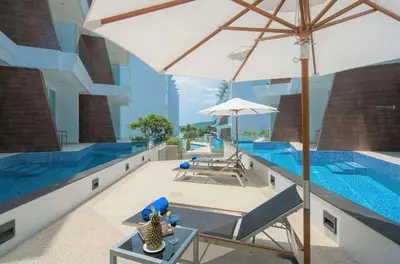 a swimming pool with an umbrella and a table at C244 Ocean Breeze 1BR Studio Steps from the Sea in Ban Saiyuan (1)
