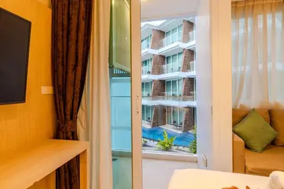 a room with a window with a view of a building at C245 Steps from the Beach Pool & Ocean View in Ban Saiyuan (1)