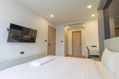 a bedroom with a white bed with a tv on the wall at C246 New 1BR Condo with Pool, Gym &Great Location in Thalang