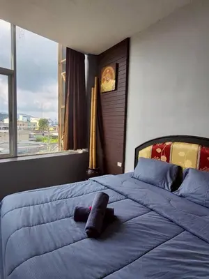 a bedroom with a large blue bed with a large window at The Rest Phuket in Phuket Town